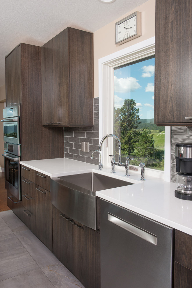 This is an example of a mid-sized contemporary u-shaped eat-in kitchen in Other with a farmhouse sink, flat-panel cabinets, dark wood cabinets, quartzite benchtops, grey splashback, glass tile splashback, stainless steel appliances, porcelain floors and with island.