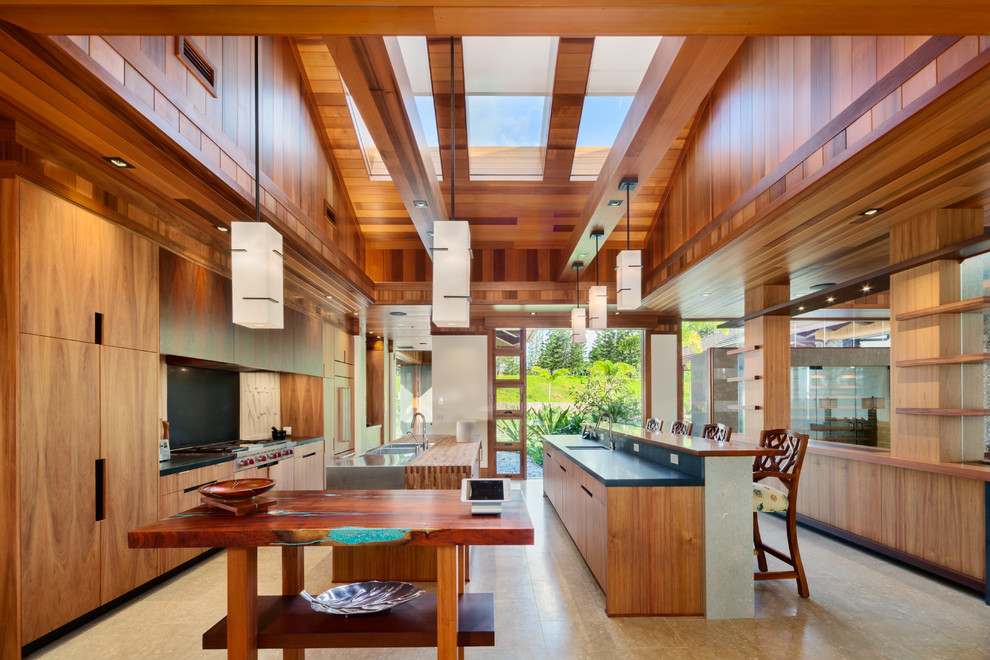 Expansive tropical galley separate kitchen in Hawaii with a double-bowl sink, flat-panel cabinets, medium wood cabinets, wood benchtops, stainless steel appliances and multiple islands.