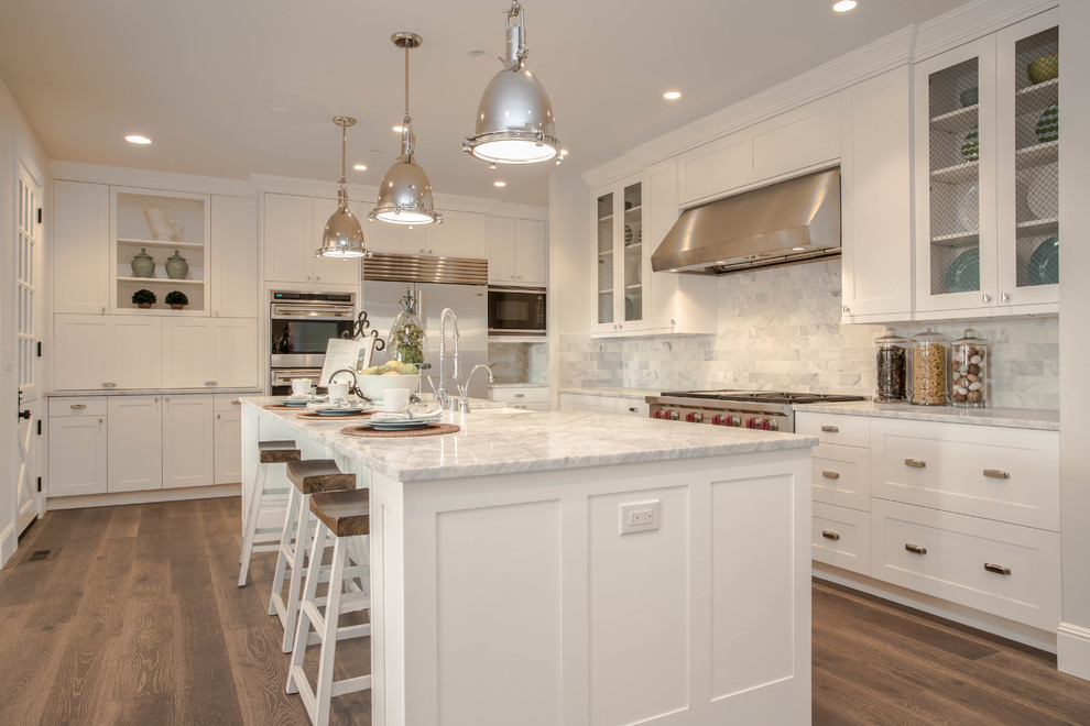 Photo of a country l-shaped kitchen in Seattle with shaker cabinets, white cabinets, marble benchtops, white splashback, stainless steel appliances, dark hardwood floors and marble splashback.