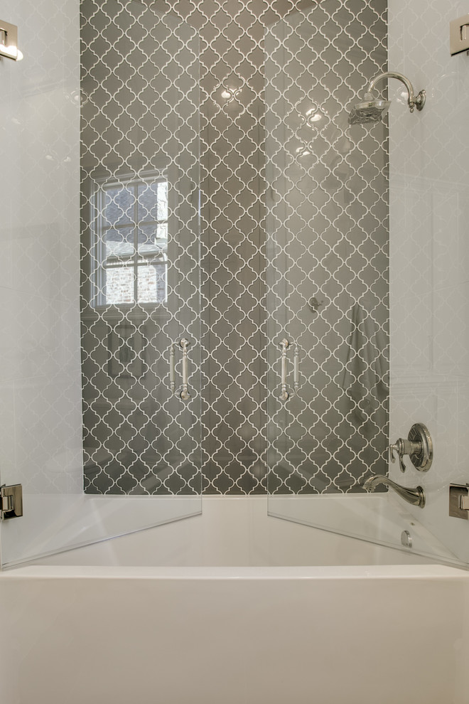 Photo of a mid-sized transitional master bathroom in Dallas with raised-panel cabinets, white cabinets, an alcove tub, a shower/bathtub combo, a two-piece toilet, gray tile, stone tile, white walls, porcelain floors, an undermount sink and marble benchtops.