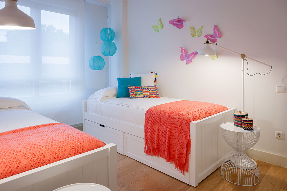 Inspiration for a small modern kids' bedroom for kids 4-10 years old and girls in Bilbao with white walls and light hardwood floors.