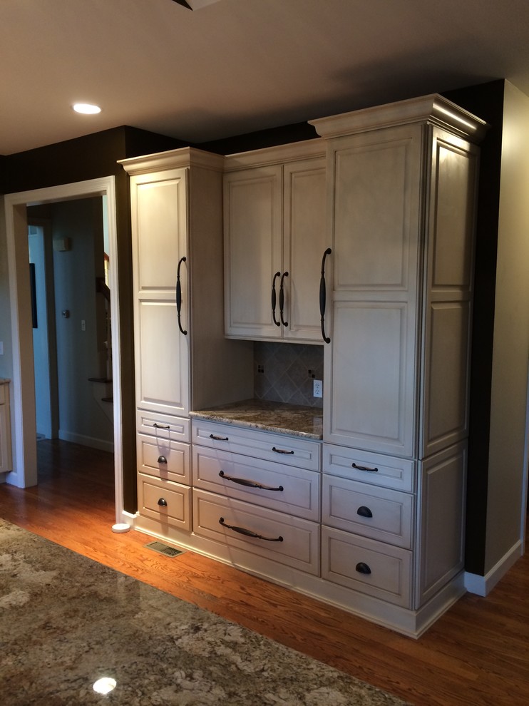 Inspiration for a transitional l-shaped medium tone wood floor kitchen remodel in St Louis with a farmhouse sink, raised-panel cabinets, granite countertops and an island