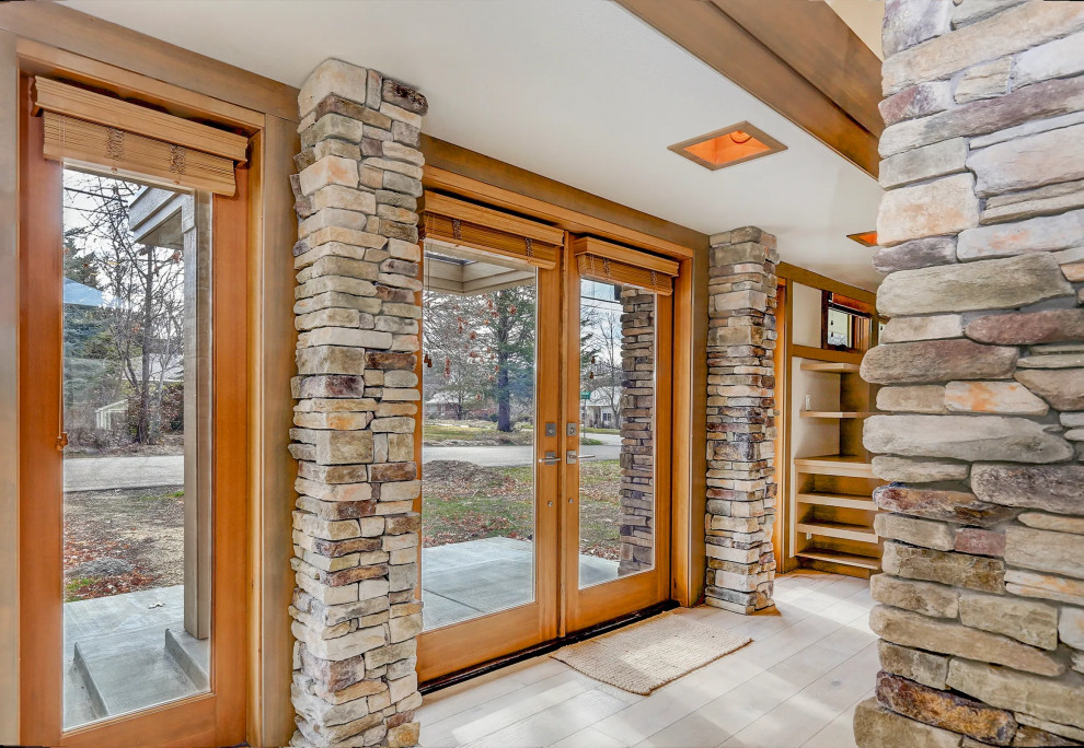 Light wood floor, brown floor and vaulted ceiling double front door photo with a medium wood front door