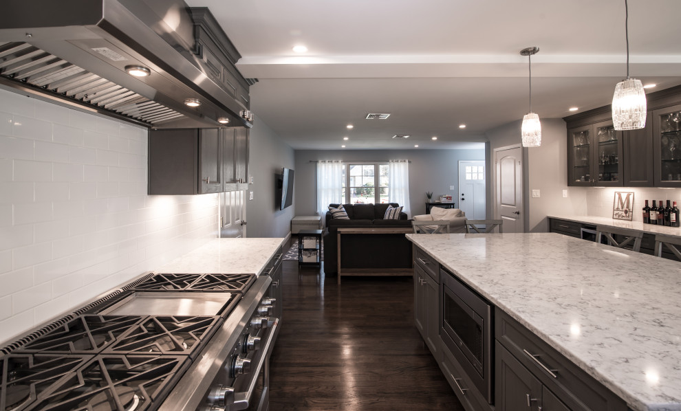 Open concept kitchen - mid-sized transitional l-shaped dark wood floor and brown floor open concept kitchen idea in New York with an undermount sink, shaker cabinets, gray cabinets, marble countertops, white backsplash, ceramic backsplash, stainless steel appliances, an island and white countertops