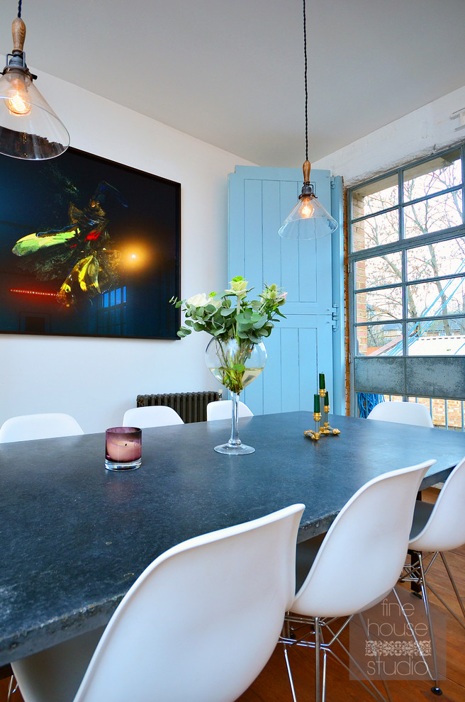 Photo of an industrial open plan dining in London with white walls and dark hardwood floors.
