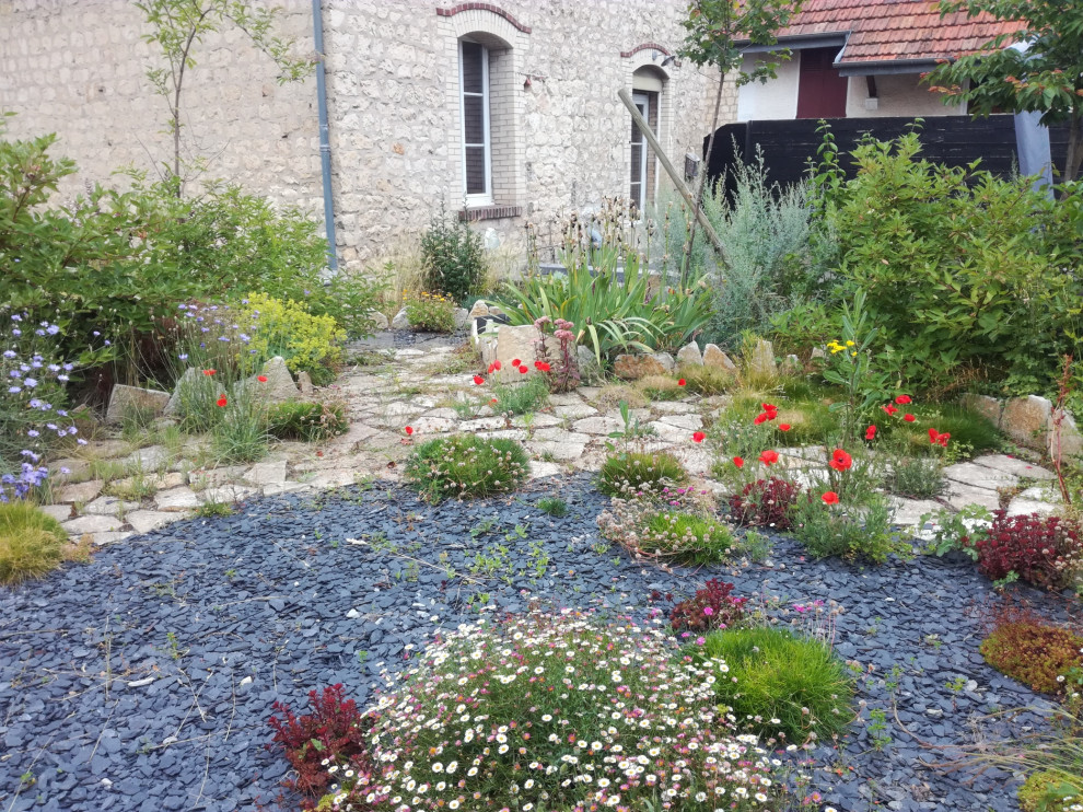 This is an example of a small modern side yard garden in Le Havre with with rock feature and mulch.