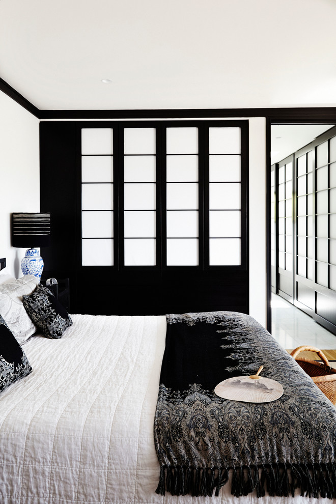 Large contemporary bedroom in Sydney with white walls and medium hardwood floors.