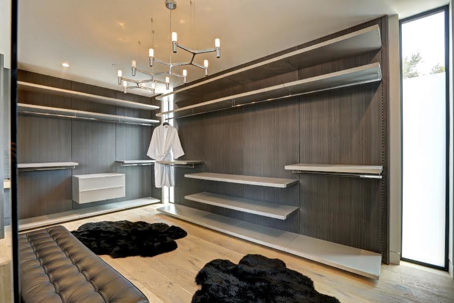 Large modern gender-neutral walk-in wardrobe in Los Angeles with flat-panel cabinets.