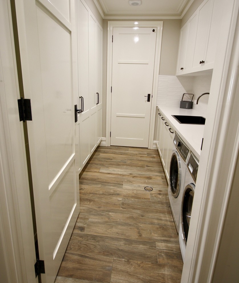 Inspiration for a large traditional galley utility room in Sydney with a drop-in sink, shaker cabinets, white cabinets, quartz benchtops, beige walls, medium hardwood floors, a side-by-side washer and dryer, brown floor and white benchtop.