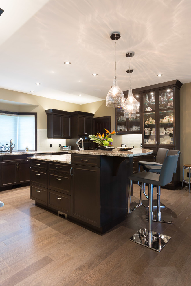 Inspiration for a large transitional l-shaped open plan kitchen in Other with an undermount sink, recessed-panel cabinets, dark wood cabinets, granite benchtops, white splashback, porcelain splashback, stainless steel appliances, light hardwood floors, with island, brown floor and multi-coloured benchtop.