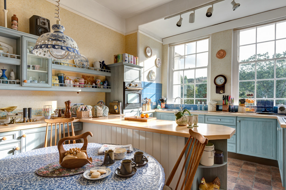 Inspiration for a traditional u-shaped eat-in kitchen in Other with recessed-panel cabinets, blue cabinets, wood benchtops and blue splashback.