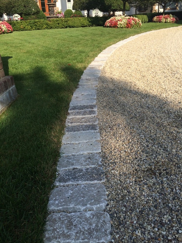 Photo of a large traditional front yard full sun driveway in Chicago with natural stone pavers.