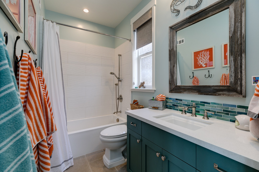 This is an example of a small beach style kids bathroom in Los Angeles with shaker cabinets, turquoise cabinets, an alcove tub, an alcove shower, a one-piece toilet, blue tile, porcelain tile, blue walls, limestone floors, an undermount sink, quartzite benchtops, beige floor and a shower curtain.