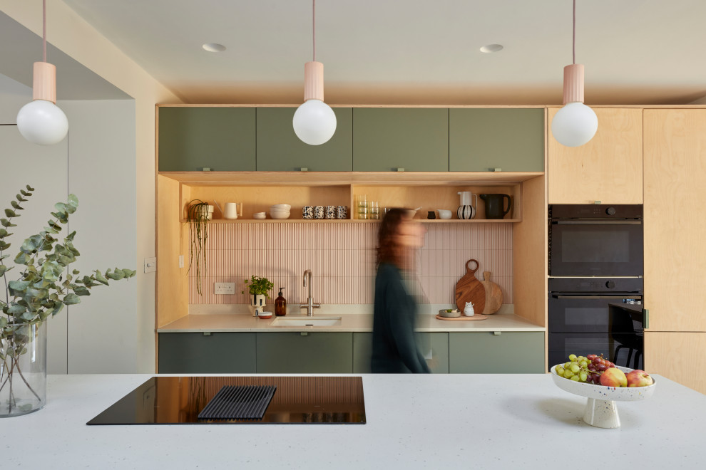 Design ideas for a mid-sized contemporary single-wall eat-in kitchen in London with an integrated sink, flat-panel cabinets, light wood cabinets, terrazzo benchtops, pink splashback, ceramic splashback, black appliances, linoleum floors, with island, grey floor, white benchtop and exposed beam.