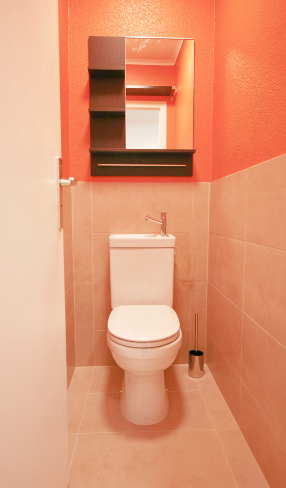 This is an example of a small contemporary powder room with orange walls, ceramic floors, an integrated sink, beige floor, beige tile, ceramic tile and a one-piece toilet.