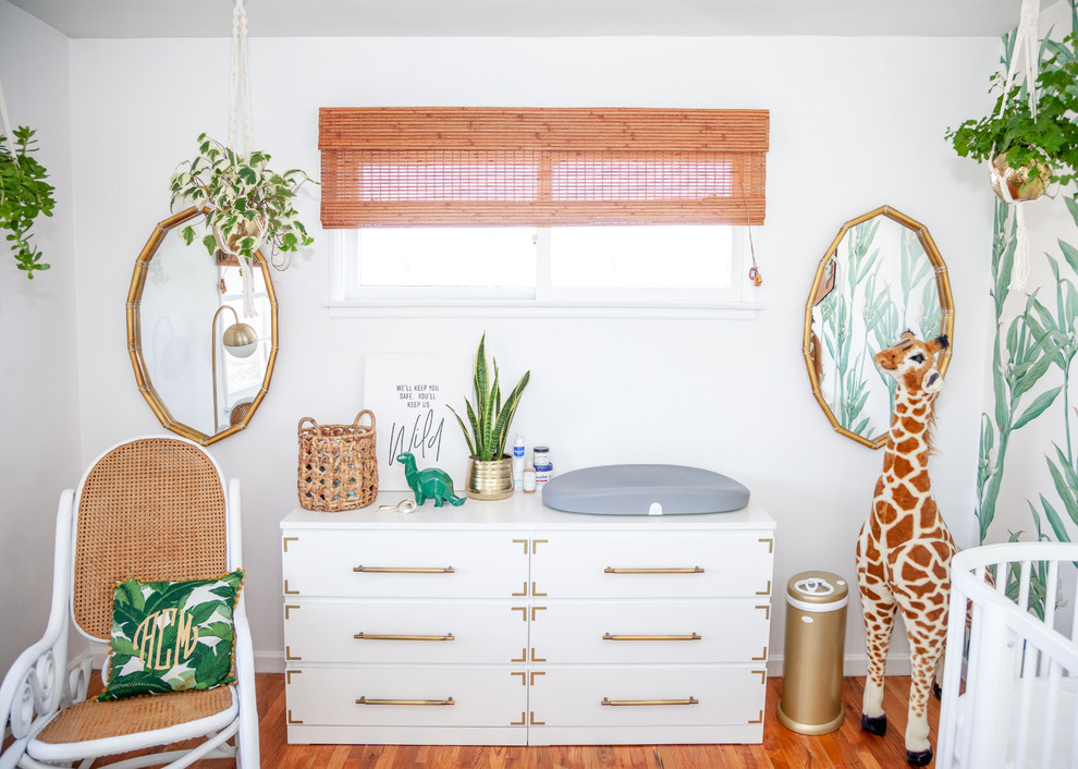 This is an example of a tropical gender-neutral nursery in Los Angeles with white walls and medium hardwood floors.