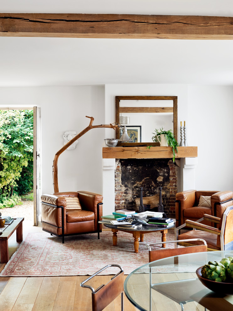 This is an example of a mid-sized midcentury open concept living room in Paris with white walls, medium hardwood floors, a standard fireplace, no tv and a library.