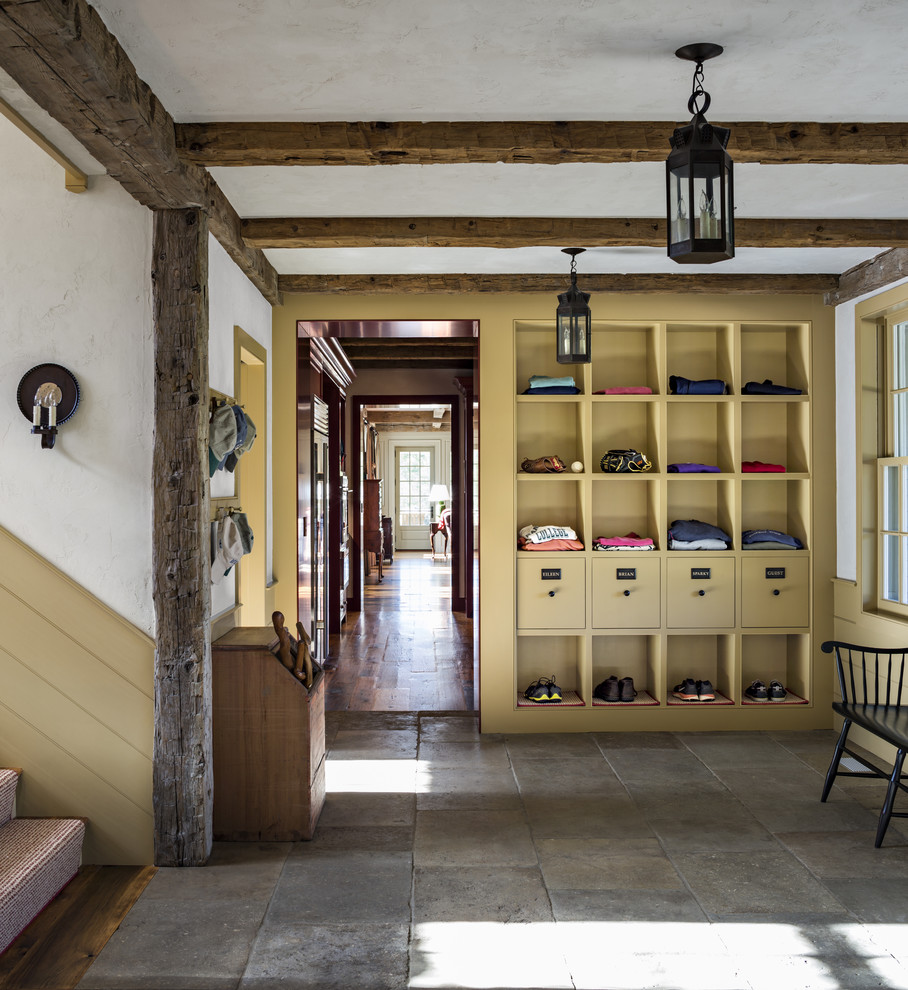 Expansive country mudroom in New York with limestone floors and white walls.