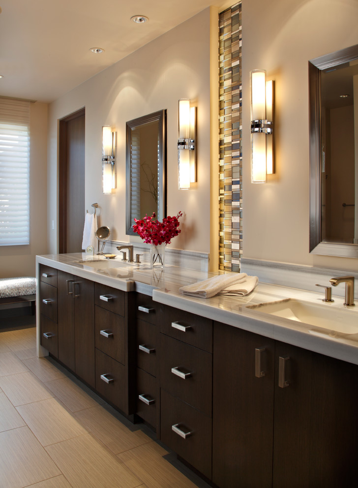 This is an example of a mid-sized modern master bathroom in Phoenix with an undermount sink, flat-panel cabinets, dark wood cabinets, limestone benchtops, a corner shower, gray tile, porcelain tile, beige walls, porcelain floors and a one-piece toilet.