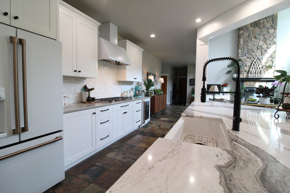 Large country l-shaped open plan kitchen in Seattle with a farmhouse sink, recessed-panel cabinets, white cabinets, quartz benchtops, multi-coloured splashback, marble splashback, white appliances, slate floors, with island, multi-coloured floor and multi-coloured benchtop.