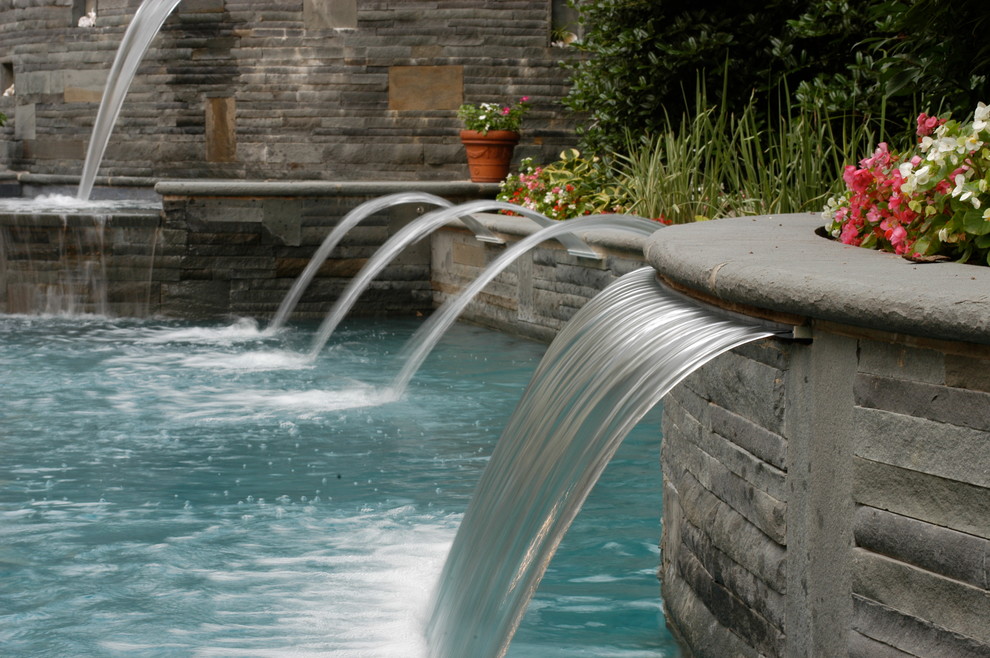 This is an example of a large mediterranean backyard custom-shaped pool in New York with a water feature.
