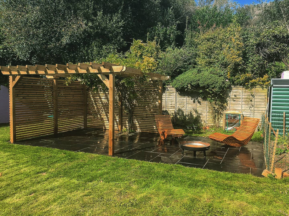 Immagine di un piccolo privacy in giardino design esposto in pieno sole dietro casa in estate con pavimentazioni in pietra naturale e recinzione in legno