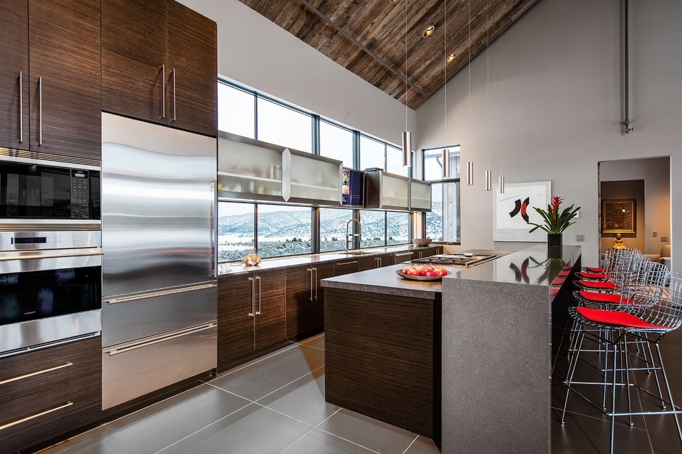 Inspiration for an expansive contemporary single-wall eat-in kitchen in Denver with an undermount sink, flat-panel cabinets, dark wood cabinets, stainless steel benchtops, window splashback, stainless steel appliances, porcelain floors, with island and brown floor.