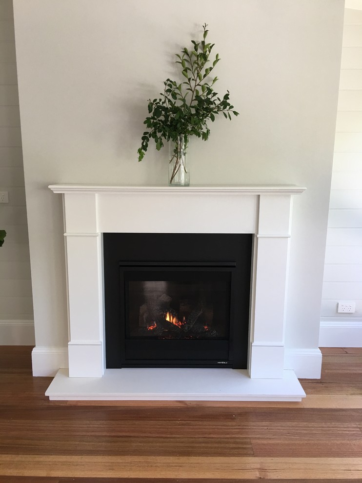 Photo of a small contemporary formal open concept living room in Wollongong with grey walls, light hardwood floors, a standard fireplace, a plaster fireplace surround, no tv and beige floor.