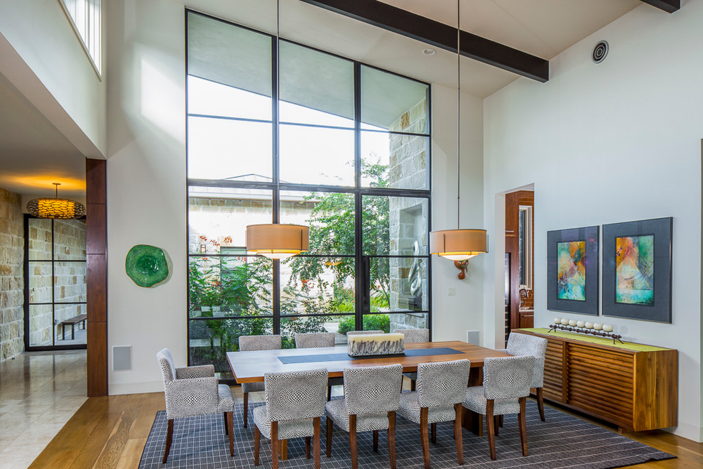 This is an example of a mid-sized contemporary open plan dining in Austin with white walls and medium hardwood floors.