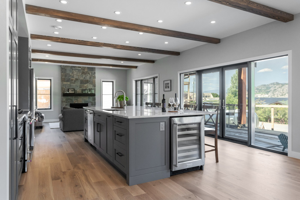 Inspiration for a mid-sized transitional single-wall light wood floor, brown floor and exposed beam eat-in kitchen remodel with an undermount sink, shaker cabinets, gray cabinets, quartzite countertops, white backsplash, subway tile backsplash, stainless steel appliances, an island and multicolored countertops
