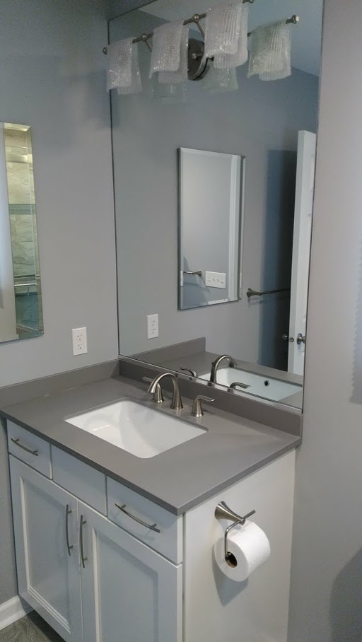 Inspiration for a mid-sized contemporary master bathroom in New York with recessed-panel cabinets, white cabinets, an alcove shower, a one-piece toilet, gray tile, ceramic tile, grey walls, ceramic floors, an undermount sink, solid surface benchtops, grey floor, a sliding shower screen and grey benchtops.
