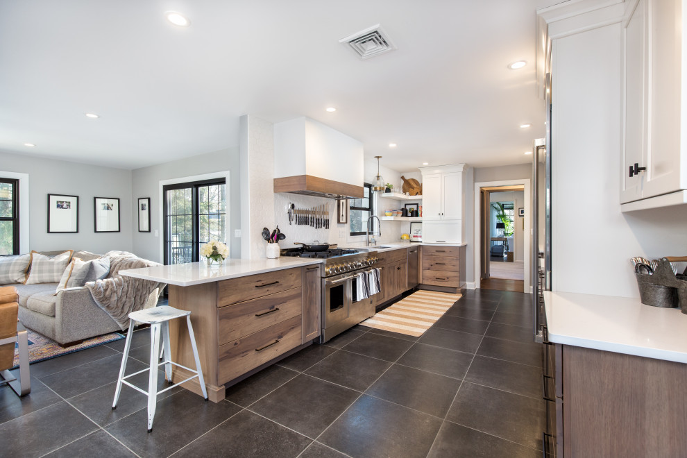 This is an example of a mid-sized transitional galley open plan kitchen in New York with an undermount sink, shaker cabinets, medium wood cabinets, quartz benchtops, white splashback, ceramic splashback, stainless steel appliances, ceramic floors, with island, grey floor and white benchtop.