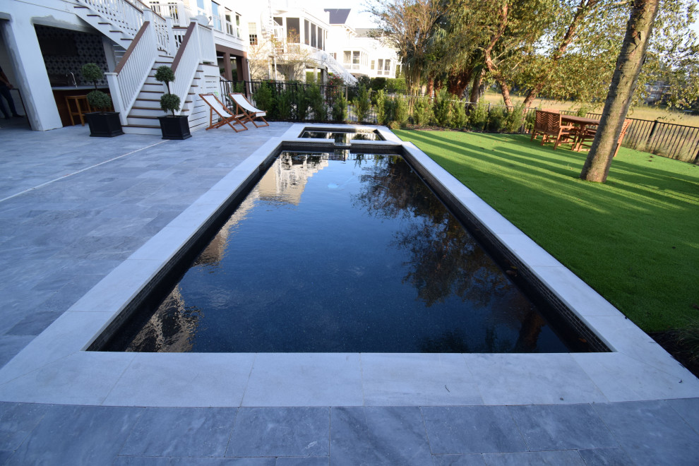 Modelo de piscina actual pequeña en patio trasero con adoquines de piedra natural