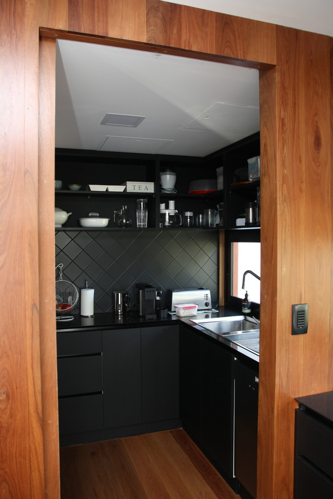 Photo of a large contemporary galley kitchen pantry in Adelaide with a single-bowl sink, black cabinets, quartzite benchtops, window splashback, black appliances, medium hardwood floors and with island.