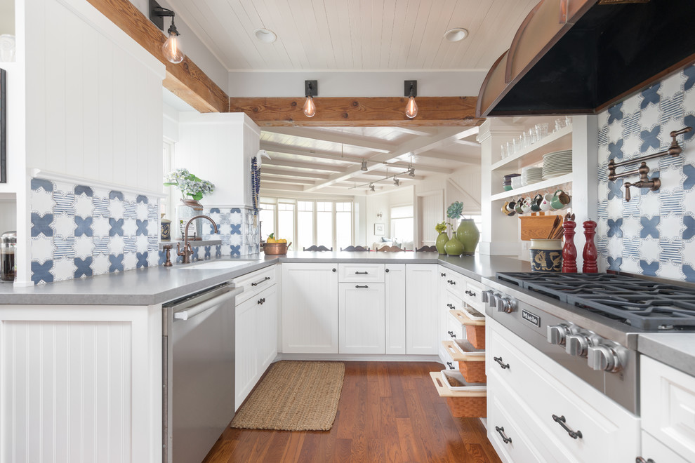 This is an example of a mid-sized beach style u-shaped kitchen pantry in San Diego with a single-bowl sink, beaded inset cabinets, white cabinets, quartz benchtops, multi-coloured splashback, terra-cotta splashback, stainless steel appliances, medium hardwood floors, no island, brown floor and grey benchtop.