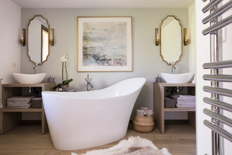 Inspiration for a mid-sized transitional master bathroom with light wood cabinets, a freestanding tub, an open shower, a wall-mount toilet, blue tile, blue walls, medium hardwood floors, a vessel sink, wood benchtops, brown floor, an open shower, brown benchtops and open cabinets.