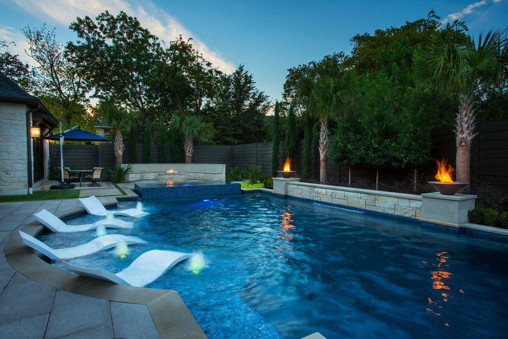 Photo of a large transitional backyard custom-shaped pool in Dallas with natural stone pavers.