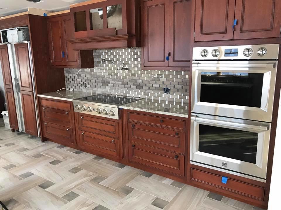 Mid-sized transitional porcelain tile and beige floor open concept kitchen photo in New York with raised-panel cabinets, medium tone wood cabinets, granite countertops, metallic backsplash, subway tile backsplash, stainless steel appliances, an island and gray countertops