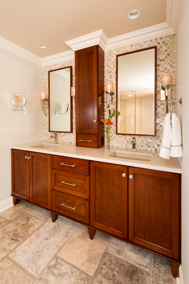 Example of a mid-sized transitional master multicolored tile and glass sheet travertine floor and beige floor freestanding bathtub design with furniture-like cabinets, medium tone wood cabinets, gray walls, a drop-in sink and quartz countertops