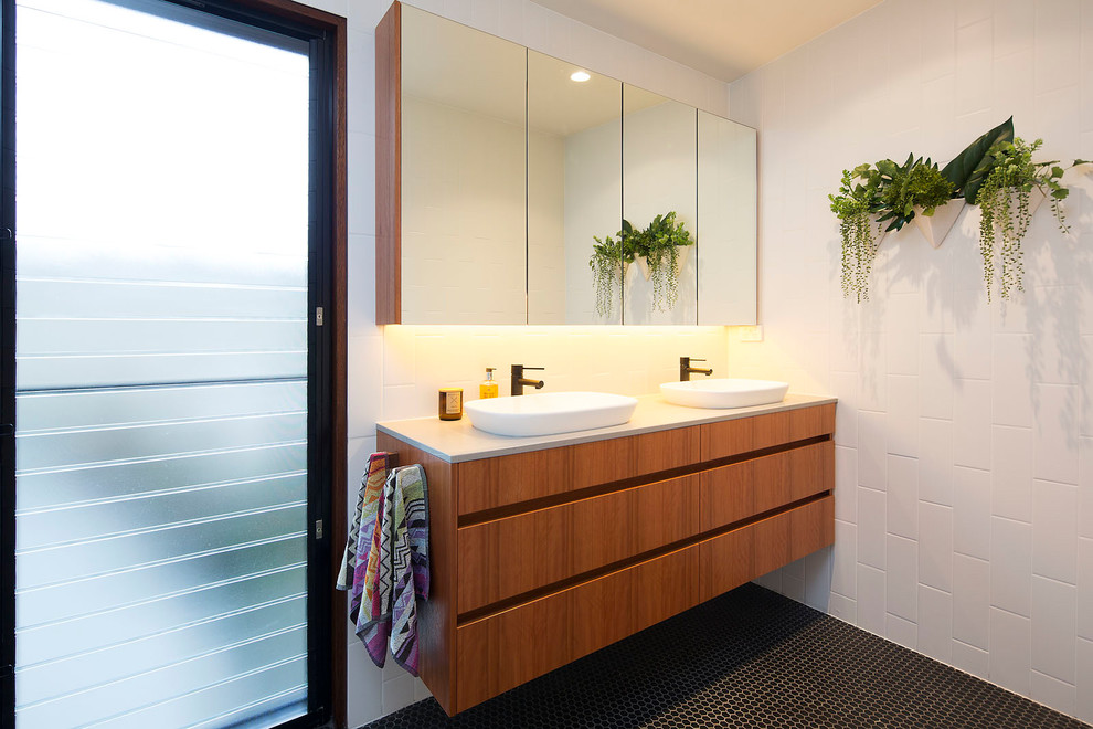 This is an example of a small contemporary master bathroom in Brisbane with medium wood cabinets, white tile, subway tile, white walls, mosaic tile floors, engineered quartz benchtops, black floor, flat-panel cabinets and a vessel sink.