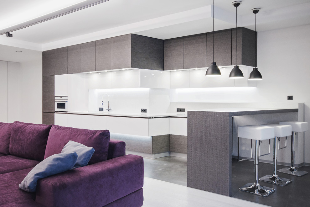 Photo of a large contemporary single-wall eat-in kitchen in Moscow with flat-panel cabinets, grey cabinets, white splashback, an undermount sink, solid surface benchtops, marble splashback, panelled appliances, porcelain floors and grey floor.