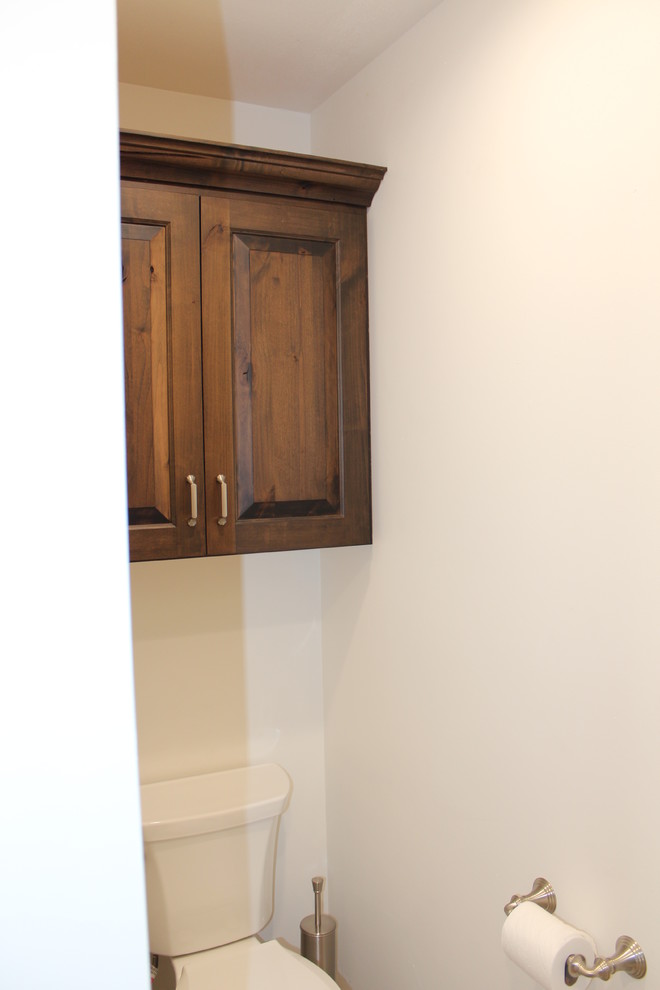 This is an example of a traditional bathroom in Other with raised-panel cabinets and brown cabinets.