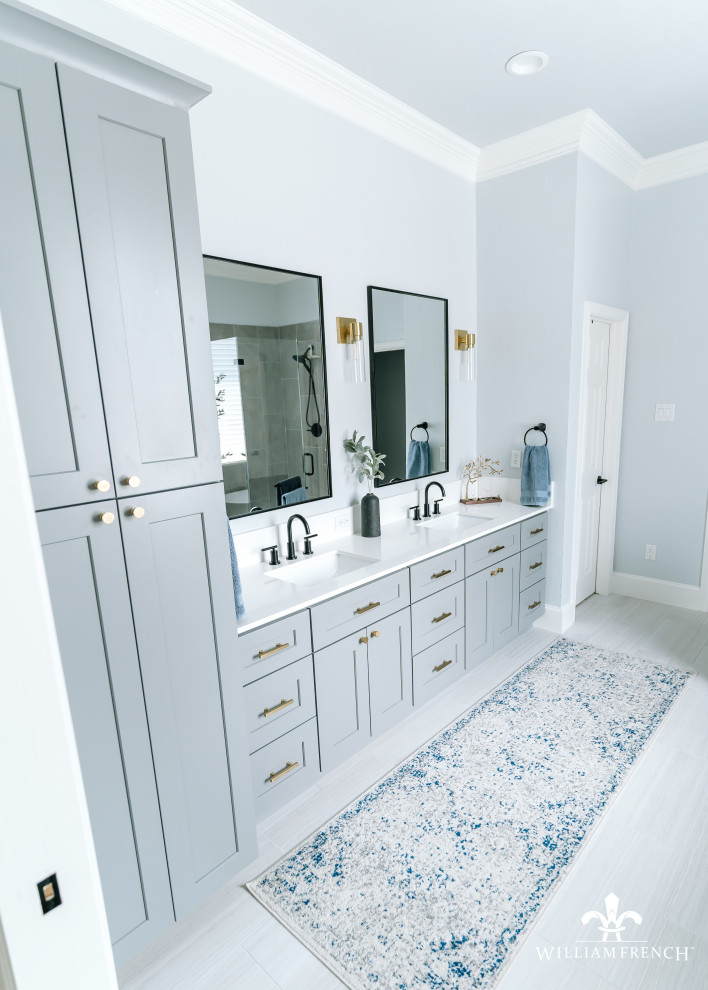 Photo of a mid-sized beach style master bathroom in Dallas with shaker cabinets, grey cabinets, a freestanding tub, a corner shower, a two-piece toilet, gray tile, porcelain tile, blue walls, porcelain floors, an undermount sink, engineered quartz benchtops, grey floor, a hinged shower door, white benchtops, a shower seat, a double vanity and a built-in vanity.
