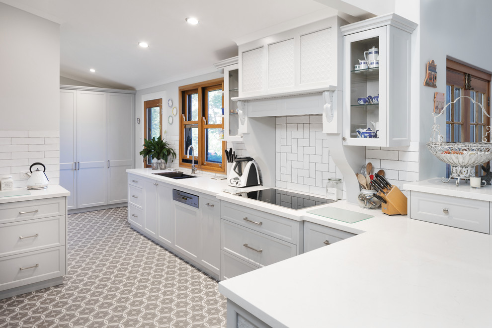 Inspiration for a traditional kitchen in Perth with shaker cabinets, quartz benchtops, white splashback, subway tile splashback, ceramic floors, an undermount sink, white cabinets, a peninsula, grey floor and white benchtop.