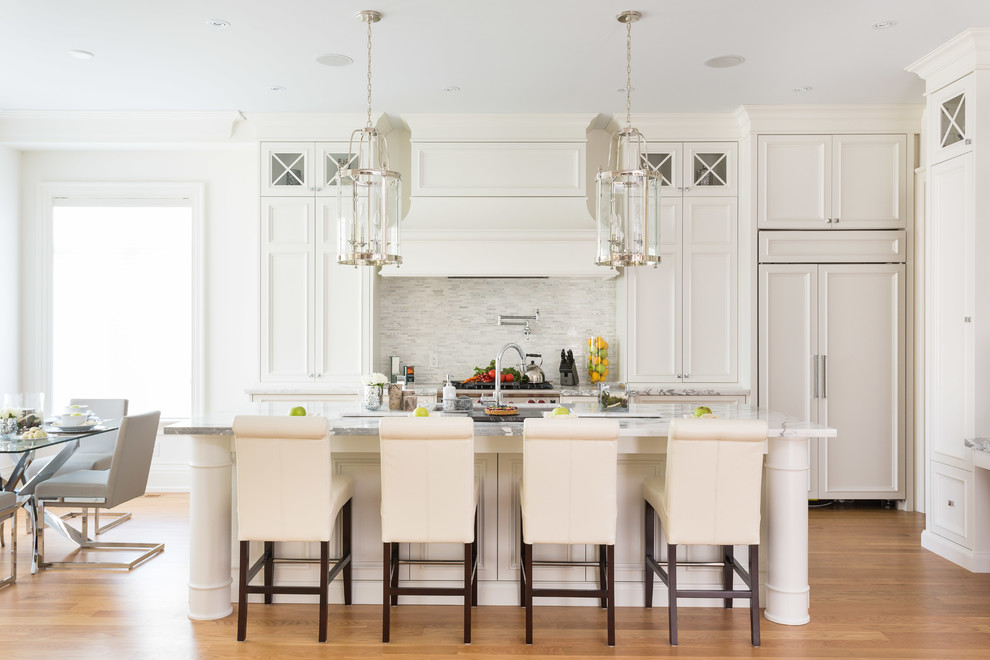 Design ideas for a traditional kitchen in Toronto with white cabinets, marble benchtops, white splashback, matchstick tile splashback, panelled appliances and medium hardwood floors.