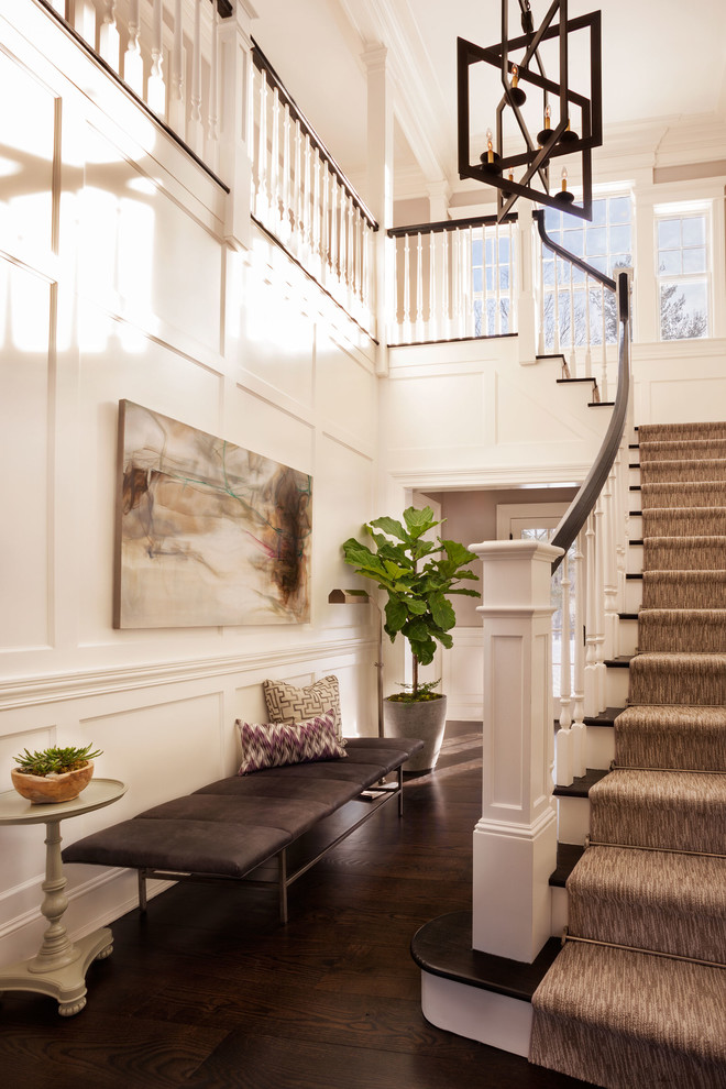This is an example of a large traditional foyer in New York with white walls, dark hardwood floors and a white front door.