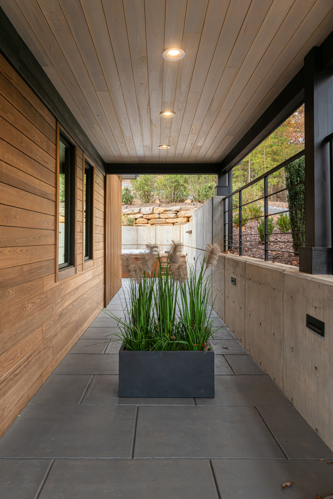 Foto di un piccolo patio o portico moderno dietro casa con un tetto a sbalzo e cemento stampato
