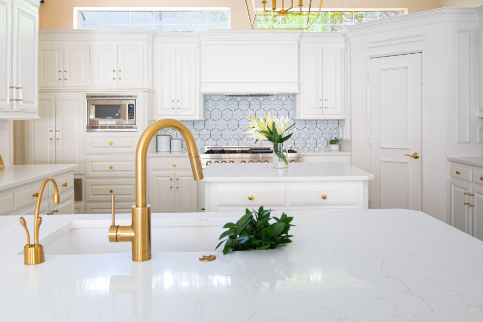 Design ideas for a mid-sized traditional kitchen in Dallas with an undermount sink, raised-panel cabinets, white cabinets, quartz benchtops, blue splashback, ceramic splashback, white appliances, multiple islands and white benchtop.