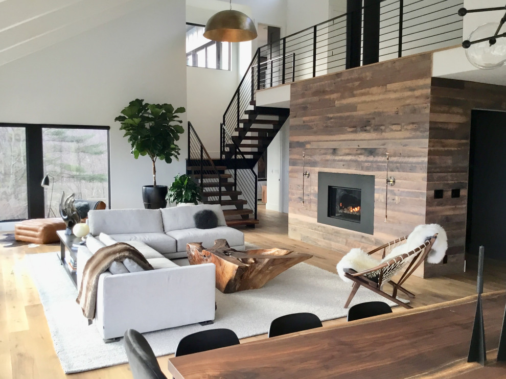 Photo of a large contemporary open concept living room in New York with medium hardwood floors, a hanging fireplace, a metal fireplace surround, no tv and brown floor.
