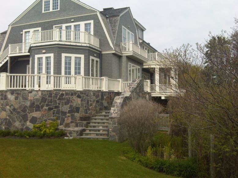 Large traditional two-storey beige exterior in Portland Maine with wood siding and a gambrel roof.